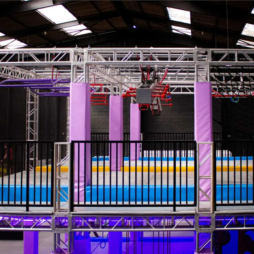La grande structure du parcours Ninja Warrior et ses agrès suspendus au-dessus des trampolines