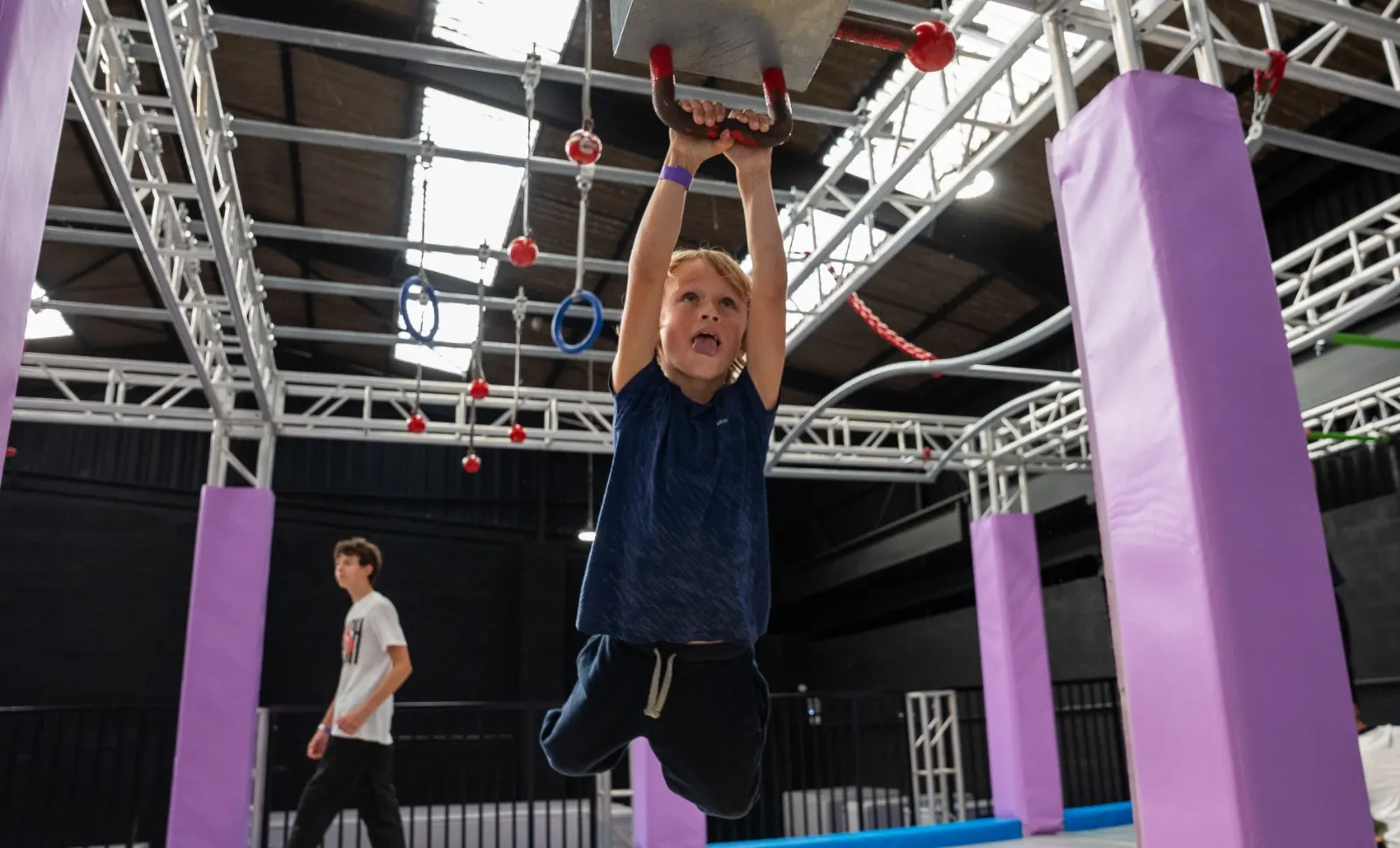 Un enfant suspendu à un anneau du parcours Ninja