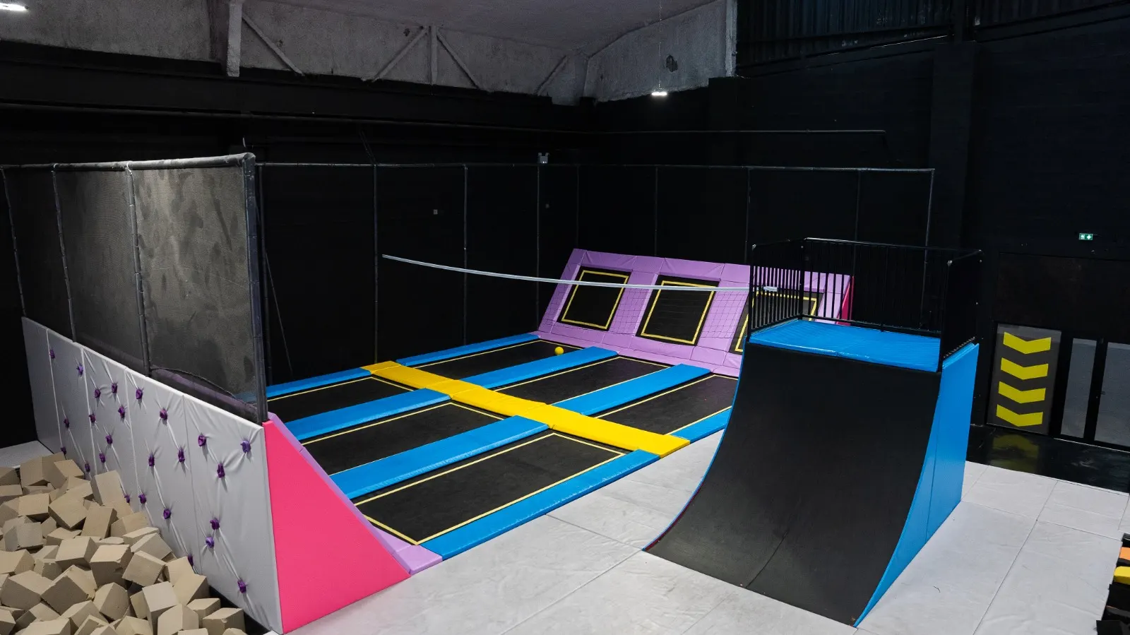 Bac à cubes de mousse au pied d’un mur d’escalade, à côté des trampolines