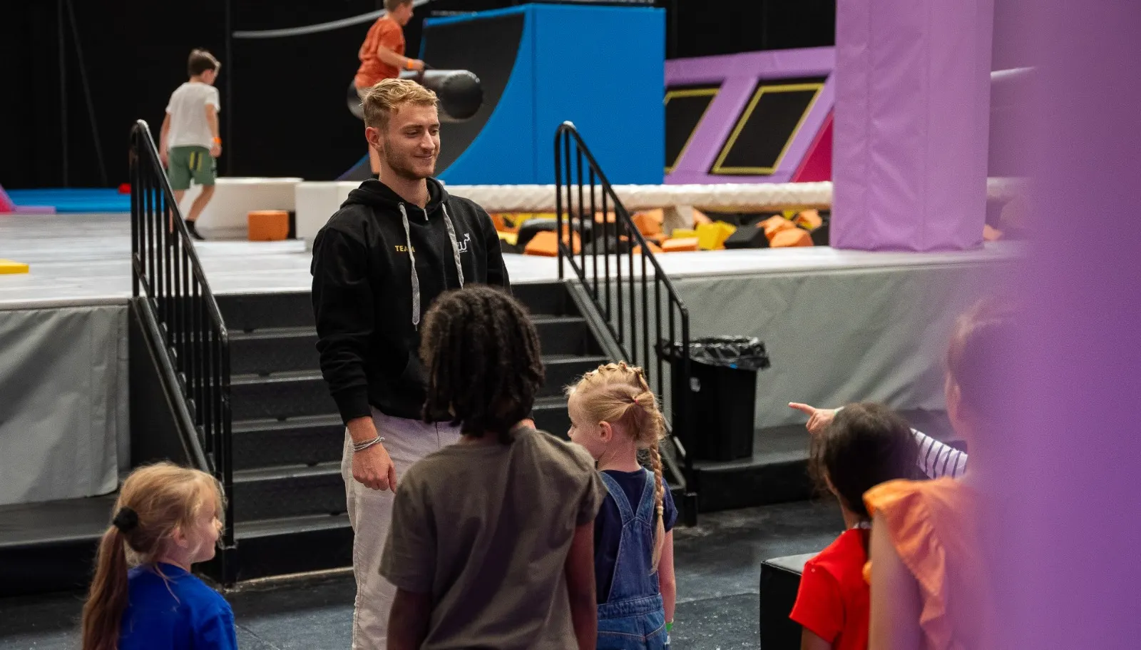 Un animateur échange avec un groupe d’enfants au bord des trampolines