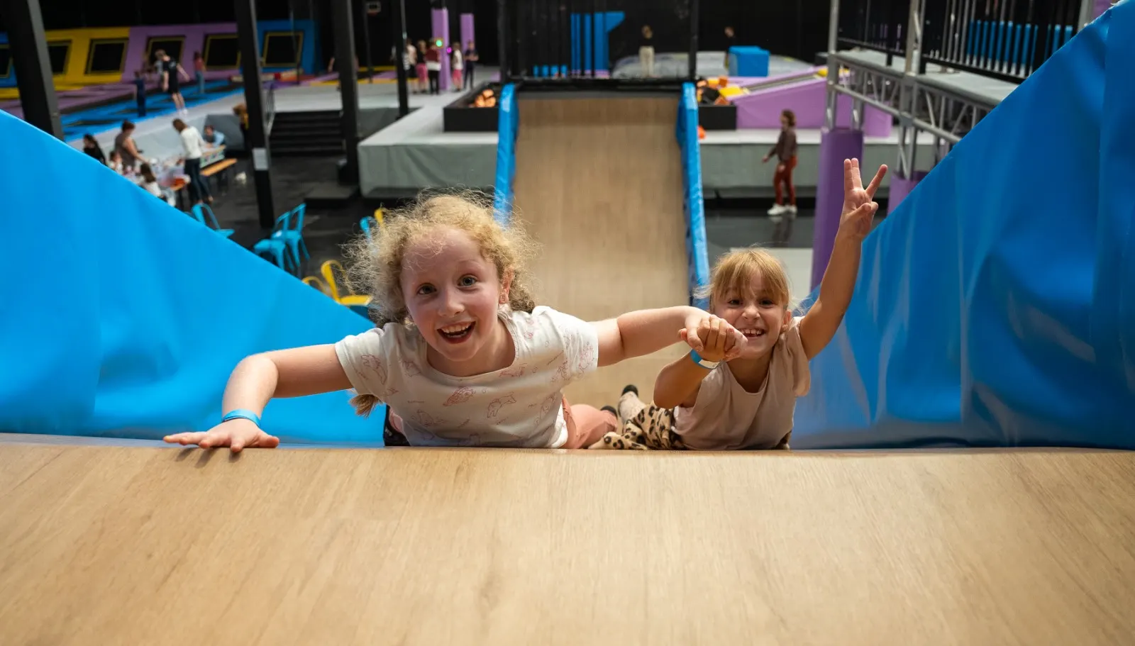 Deux enfants grimpent un plan incliné entre des protections bleues