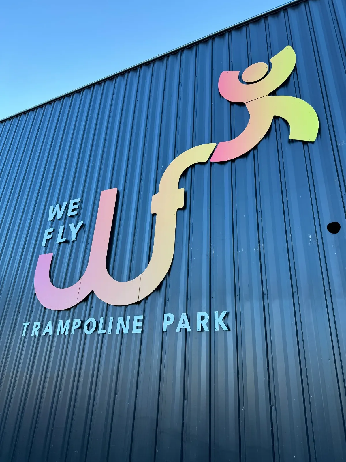 Logo We Fly Trampoline Park sur la façade bleue du bâtiment